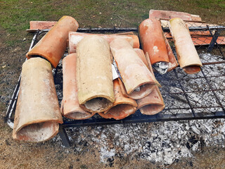 Close-up of tiles on a grill for preserving grilled food. A top-down view of a campfire for roasting and cooking vegetables. Healthy eating and the art of cooking food outdoors. Earth oven.