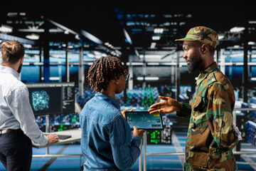 Military technicians in data center reviewing drone surveillance footage on laptop screen. Army unit officer in high tech server farm doing battlefield reconnaissance operations via drone control.