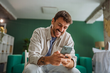 Happy man using smart phone at home is dreaming of future