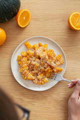 Healthy orange pumpkin salad with honey, orange and sesame seeds on wooden table with fresh citrus