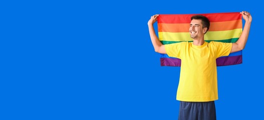 Young man with LGBT flag on blue background with space for text