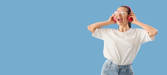Young woman in headphones singing and listening to music on blue background with space for text