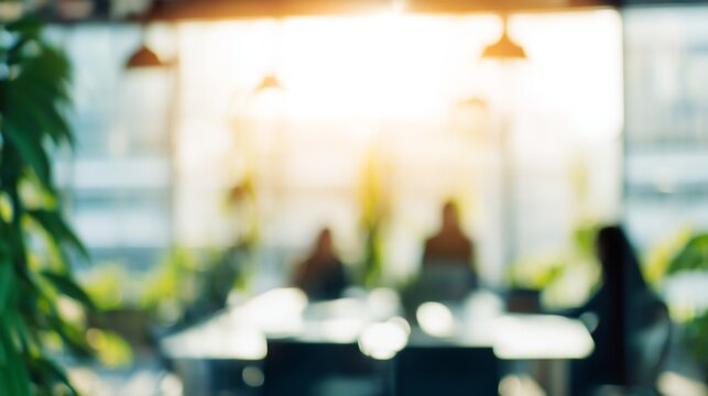 Blurred office scene capturing collaborative meeting in modern coworking environment, sunlight streaming through windows, green plants softening professional workspace