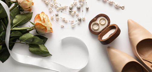 Box with wedding rings, jewelry, roses and heels on white background. Top view