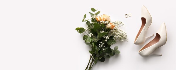 Bouquet of roses, wedding rings and female high heels shoes on white background with space for text