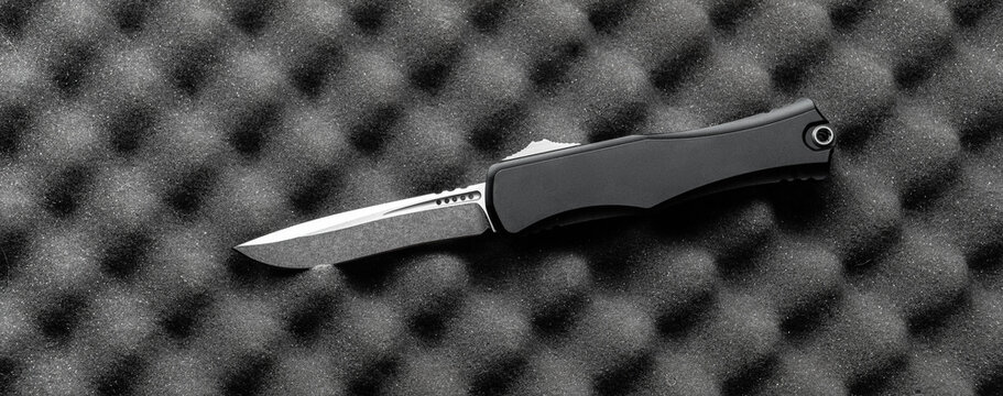 Black OTF Knife on a Foam Background - Powered by Adobe