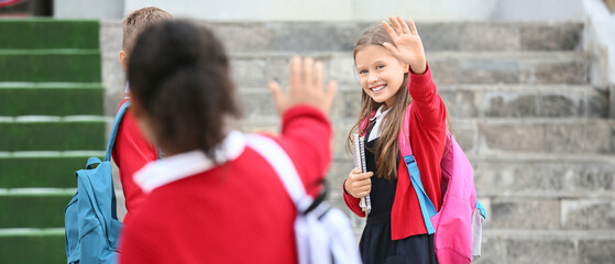 Obraz premium Group of happy pupils meeting before school outdoors