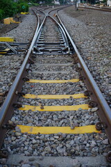 A low-angle, eye-level shot of a railway track switch, with bright yellow markers on the concrete sleepers. The image suggests a decision point, travel, or the journey ahead