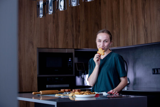 A joyful young girl is happily holding a plate full of freshly baked cookies in a modern kitchen setting