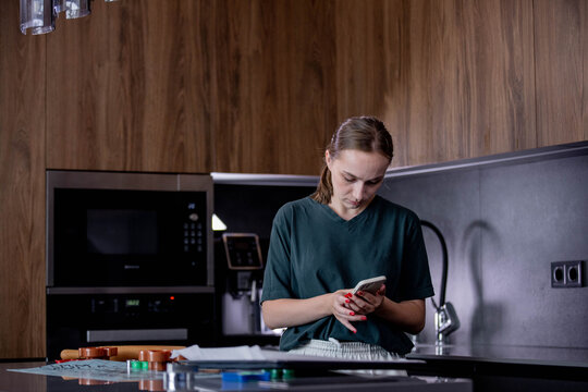 A person is seen using a modern smartphone while situated in an elegantly designed kitchen