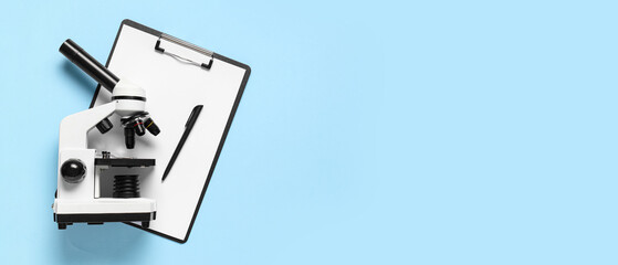 Modern microscope and clipboard on light blue background with space for text