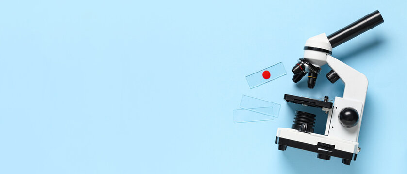 Microscope and blood sample on blue background with space for text