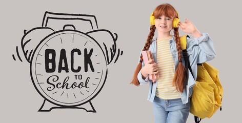 Teenage redhead girl in headphones, with books and backpack on grey background. Back to school