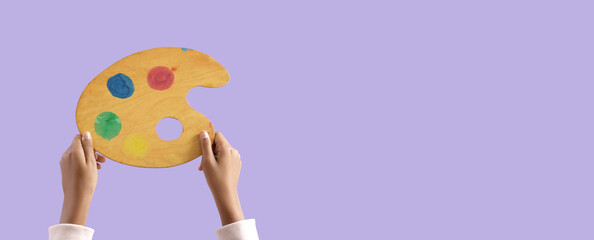 Child with paint palette on lilac background