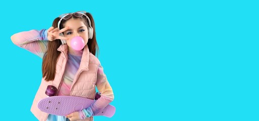 Trendy teenage girl chewing gum while showing victory gesture on blue background with space for text