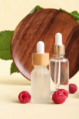 Bottles of cosmetic raspberry oil on yellow background