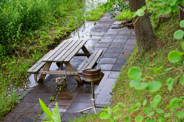 Wet wooden picnic table with benches and fire pit after rain