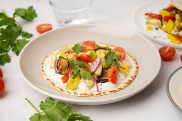 Plate of tasty pita bread with grilled vegetables on white background