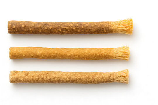 Three traditional miswak chewing sticks, a natural toothbrush for oral hygiene, isolated on a white background.