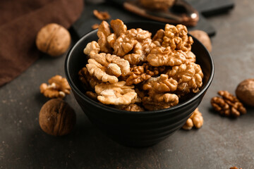 Bowl of tasty walnuts on grey background