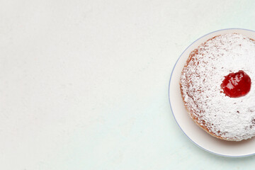 Tasty donut with jam for Hanukkah celebration on light blue background