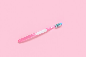 Pink plastic toothbrush on color background.