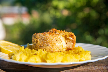 Baked fish with smashed potatoes and lemon on a plate, healthy lunch..