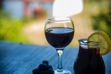 Black blackberry wine in a glass on a wooden table