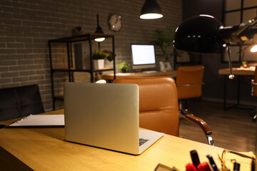 Modern laptop on table in office at night, closeup