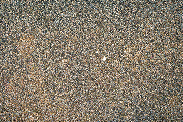Close-up of an exposed aggregate concrete surface with small stones embedded, forming a rough textured background.