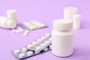 Blister packs and bottles with pills on purple background