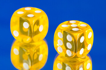 Two yellow dice, game token on blue background with water drops.