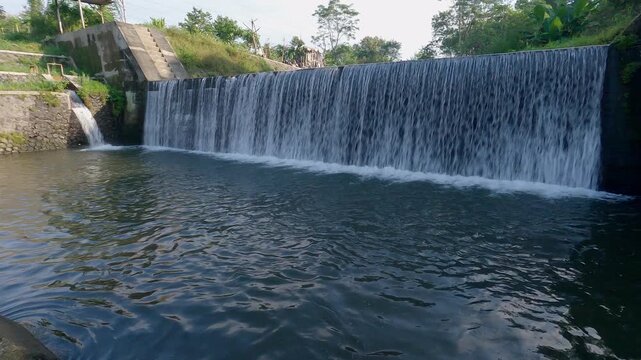 Water dam view in tropical countryside with bridge built structure. Panning left to right view