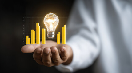 Person holds glowing light bulb above bar graph, symbolizing innovative ideas and growth in business. image conveys sense of creativity and progress in data analysis
