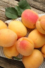 Fresh apricots and green leaves on wooden table, flat lay