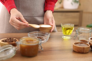 Obraz premium Making natural scrub. Woman adding sugar into bowl at wooden table, closeup