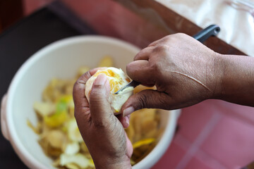 Martinique. Close-up of hands peeling a citrus fruit with a knife over a bowl during food preparation