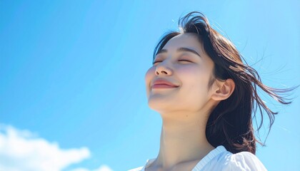 快晴の中で髪を風になびかせた若い日本人女性,A young Japanese woman with her hair blowing in the wind under a clear blue sky.	