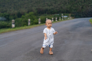 Toddler learning to walk on a mountain road in asia