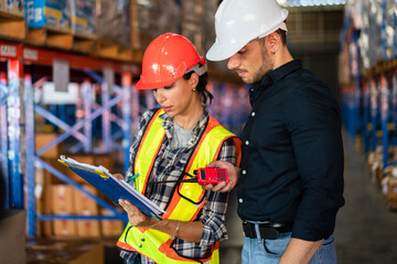 Warehouse supervisor and female operator reviewing documents. Concept of teamwork, training, and logistics management in an industrial environment
