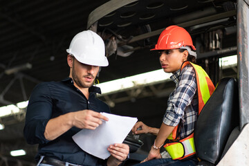 Warehouse supervisor and female forklift operator reviewing documents. Concept of teamwork, training, and logistics management in an industrial environment