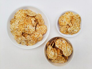 Tempeh chips in white plates and white bowl on white background. Top of view. 