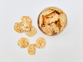 Tempeh chips in a white bowl on a white background. Top of view. 
