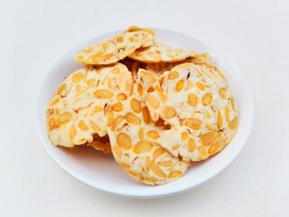 Close-up of tempeh chips in a small white plate on a white background. 