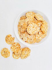 Tempeh chips in a white plate on a white background. Top of view. 