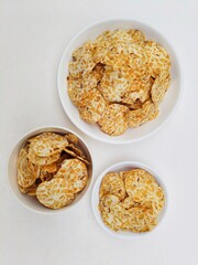 Tempeh chips in white plates and white bowl on white background. Top of view. 