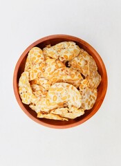 Tempeh chips in a wooden plate on a white background. Top of view. 