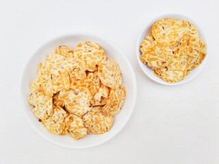 Tempeh chips in white plates on white background. Top of view. 
