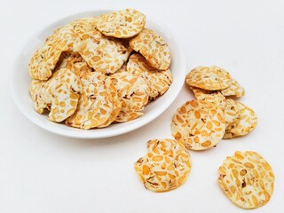 Tempeh chips in a white plate on a white background.
