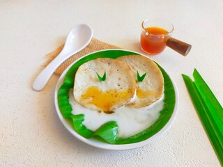 Serabi kuah, serabi with sweet coconut milk sauce in an isolated white plate. pancakes, serabi gravy, traditional Indonesian food.